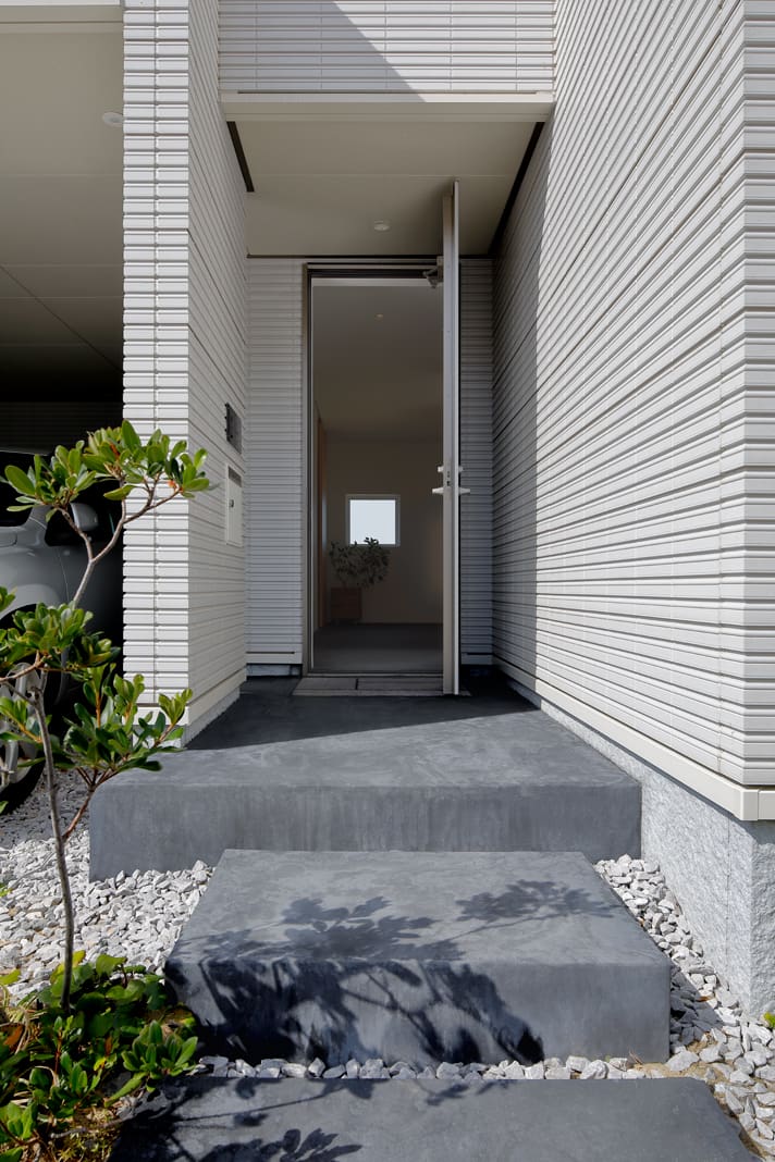 玄関はあえて光を抑え、リビングの風景へと、よりドラマチックに展開するための空間としている。