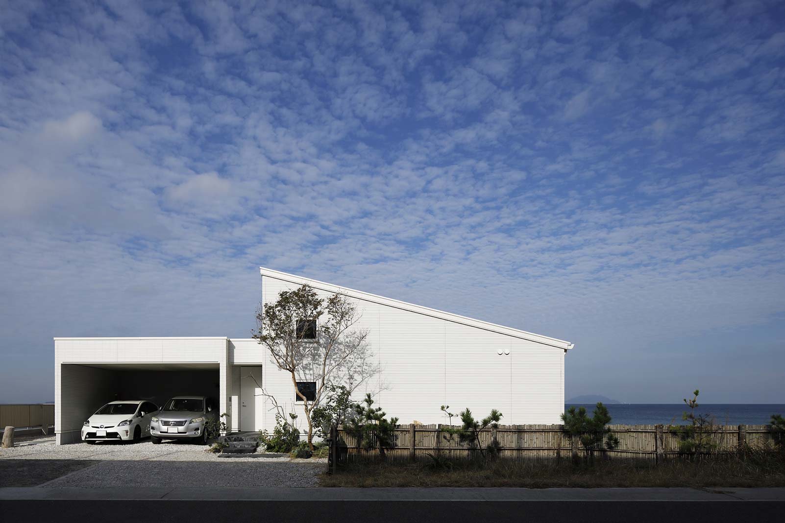 道路側から見るシルエットは、片流れ屋根を採用した平屋のゆったりとした佇まいとし、ガレージは塩害に配慮して海と反対側を開口部に。青い空に美しく映える白い外壁を施している。