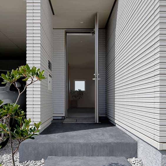 玄関はあえて光を抑え、リビングの風景へと、よりドラマチックに展開するための空間としている。