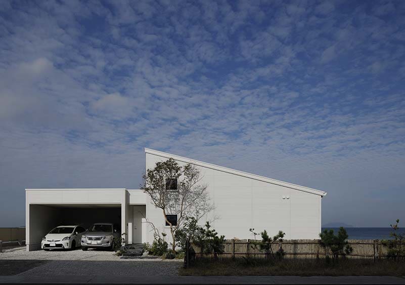 道路側から見るシルエットは、片流れ屋根を採用した平屋のゆったりとした佇まいとし、ガレージは塩害に配慮して海と反対側を開口部に。青い空に美しく映える白い外壁を施している。
