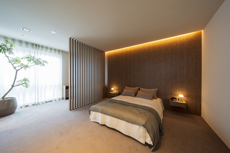 床にはカーペット、壁には木調リブパネルと間仕切格子で木質感のあるパウダーコーナーを兼ね備えた寝室となっています。