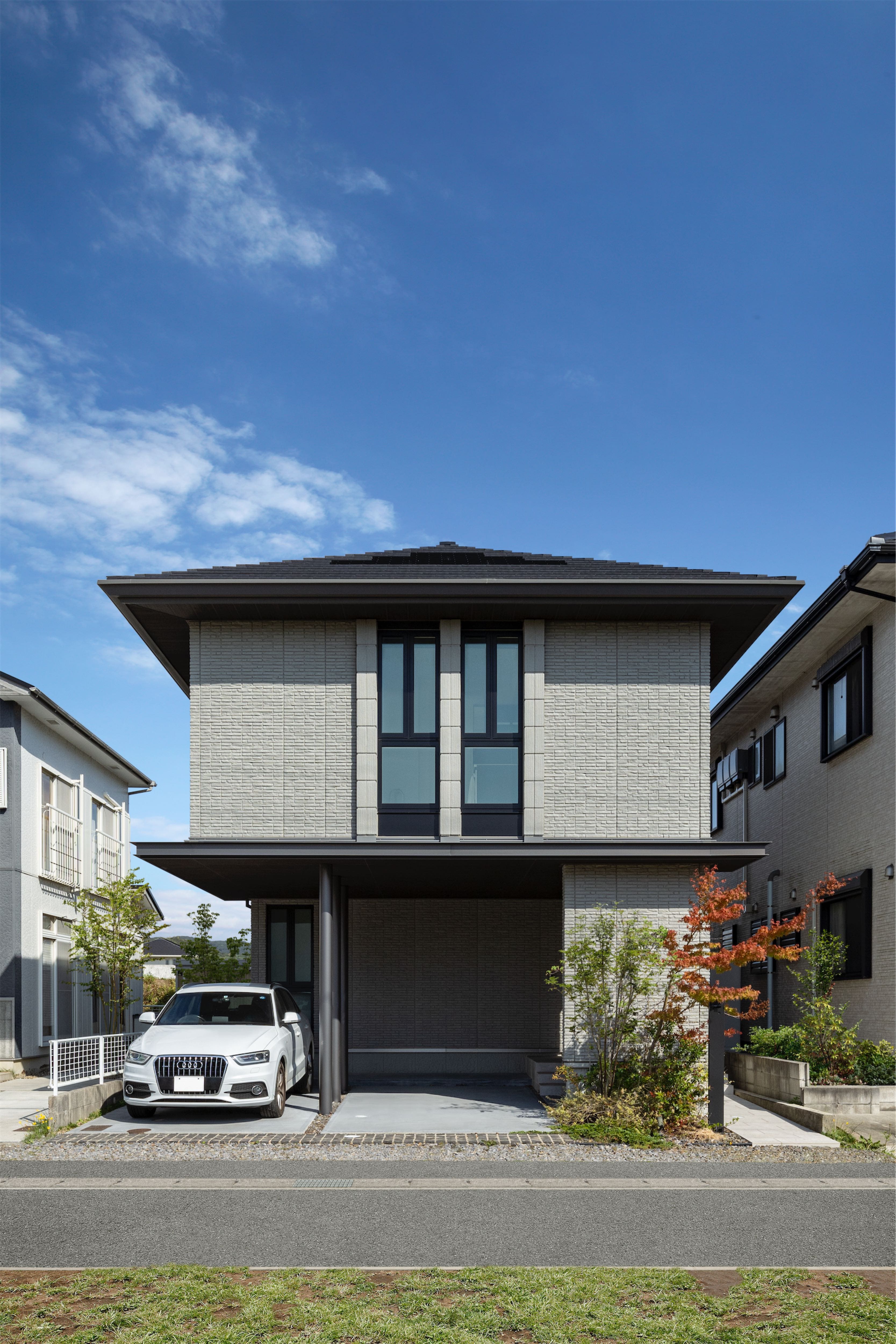 建物の1階と2階を水平方向にスライドさせることで、1階では屋根のかかった駐車スペース、2階ではバルコニーが実現した